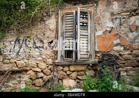 Old shuttered window and crumbling stone wall covered in vines in the Anafiotika district beneath the Acropolis in Athens, Greece. Stock Photo