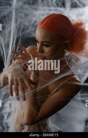Red-haired woman entangled in a net trap amid a dramatic backdrop Stock Photo