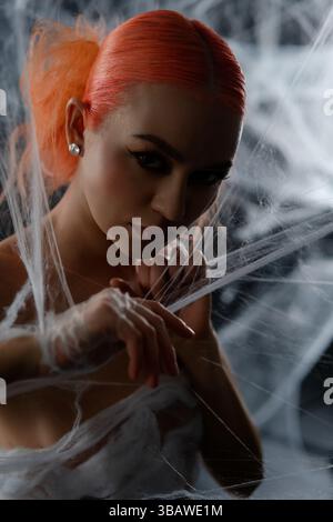 Red-haired woman entangled in a delicate web during a mysterious night Stock Photo