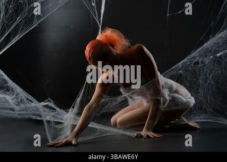 Red-haired woman entangled in a net trap surrounded by synthetic webbing Stock Photo