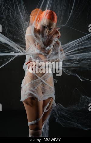 Red haired woman ensnared in a delicate web of net trap Stock Photo