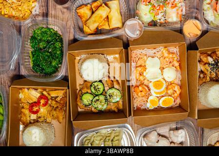 Typical Asian dishes, freshly cooked and packaged in plastic and cardboard for home delivery seen from the top Stock Photo