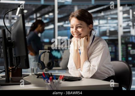 Jolly engineer in server hub satisfied by improved system efficiency metrics. Cheerful woman working in data center pleased by enhanced network infrastructure performance after finishing update Stock Photo