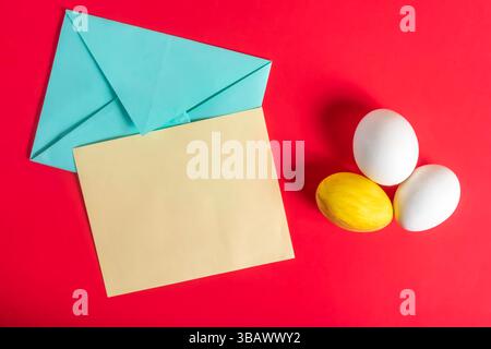 Easter themed flat lay showcasing colorful eggs, a pastel envelope, and a bright red surface. Stock Photo