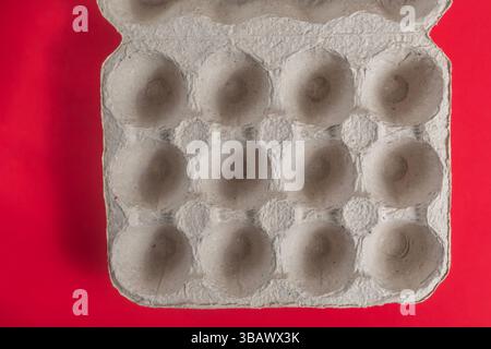 A close-up of an empty eco-friendly cardboard egg carton against a red background. Stock Photo