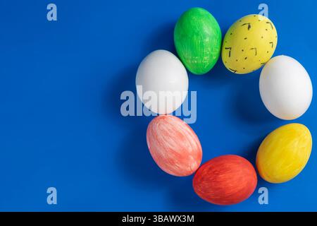 A vibrant array of painted Easter eggs in a circular pattern on a vibrant blue background. Perfect for seasonal and festive themes. Stock Photo