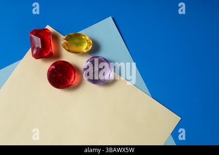 The top view of four gemstones in vibrant colors placed on a blue and yellow paper background shows beauty and elegance. Stock Photo