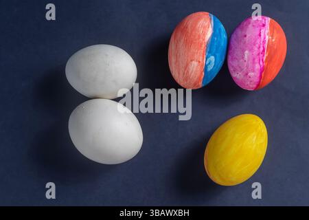 Collection of colorful and white eggs arranged on a dark blue background, representing creativity and Easter celebrations. Perfect for holiday, art, s Stock Photo