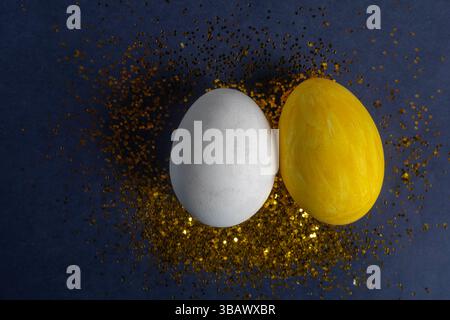 Festive arrangement of yellow and white eggs painted with gold glitter on a dark surface. For holiday decor and celebration of seasonal joy. Stock Photo