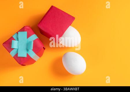 Brightly colored gift boxes and white eggs were arranged on a vibrant orange surface depicting Easter joy. Stock Photo