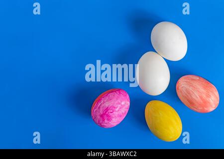 A top view of Easter eggs painted with white eggs on a bright blue background, conveying the festive spirit of Easter celebrations. Stock Photo