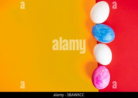 Colorful Easter eggs arranged in a row on a split red and yellow background. Perfect for spring themes. Stock Photo