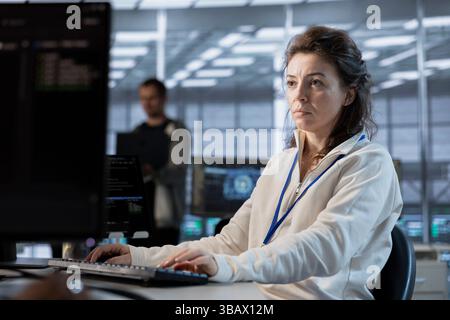 Data center programmer writing disaster recovery plans ensuring minimal downtime. Woman in server farm workplace uses analytics to monitor performance and predict future infrastructure needs Stock Photo