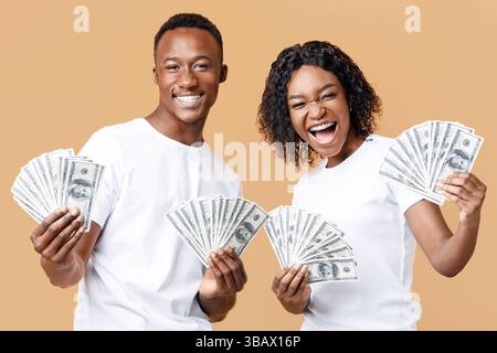 Joyful black couple won lottery, showing prize at camera, screaming Stock Photo