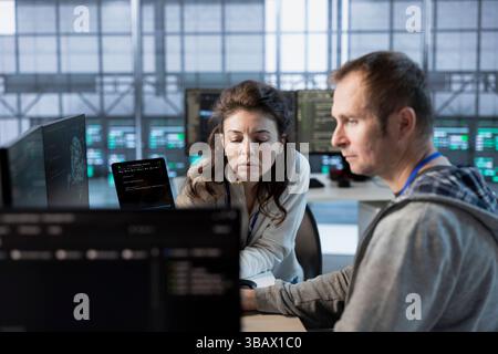 Team leader showing intern how to use machine learning to optimize data center operations. Close up of supervisor talking with employee implementing server virtualization Stock Photo