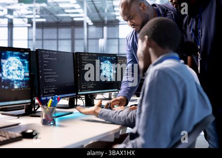 Teamworking coworkers doing brainstorming in server room, creating high performance AI systems on PC. Team of technicians in data center discussing with coworker, developing artificial intelligence Stock Photo