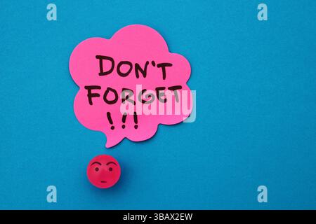 Worried face next to a speech bubble with the phrase DONT FORGET Stock Photo