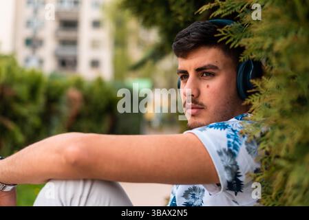A young man enjoying while listening music in the city park. Stock Photo