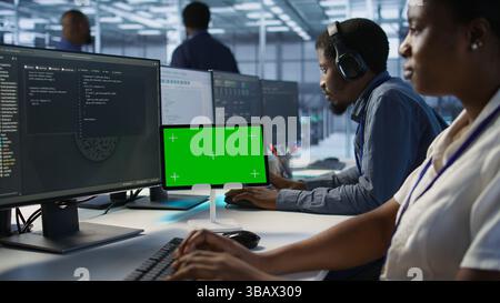 Close up of green tablet in server room used by system administrators to ensure minimal downtime. Data center software developers looking at chroma key device, monitoring performance, camera A Stock Photo