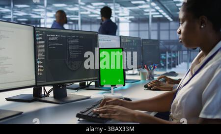 Programmers use isolated screen tablet in server room, developing disaster recovery plans ensuring minimal downtime. Data center employee looking at chroma key device, monitoring performance, camera A Stock Photo
