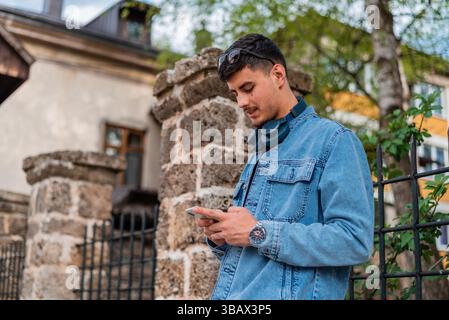A young happy urban stylish man using a phone mobile in the city street. Stock Photo
