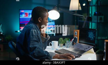 AI expert writes code on laptop in apartment office using Java programming languages. Artificial intelligence programmer remotely working on fixing database errors while working from home, camera A Stock Photo
