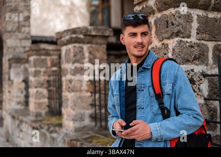 A young urban stylish man using a phone in the city street. Stock Photo