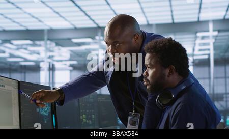 Data center manager helps intern implement AI predictive maintenance systems. Server farm supervisor checks work done by employee using artificial intelligence to identify hardware failures, camera A Stock Photo