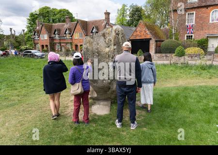 Tour group gathered around & touching the Blacksmith's Stone at the Avebury Henge & Stone Circle World Heritage Site, Wiltshire, UK Stock Photo