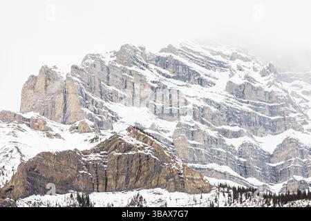 Mountain peak during the cold, foggy, and snowy winter in Banff Alberta Stock Photo