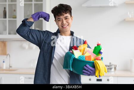 Positive asian guy with cleaning supplies showing muscles Stock Photo
