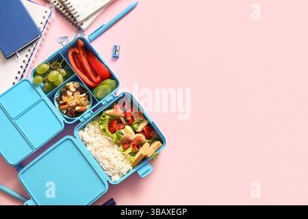 Lunchbox with delicious food and different stationery on pink background Stock Photo