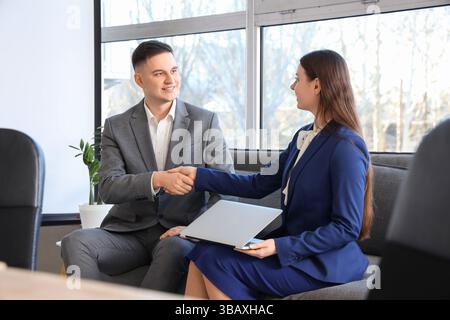Business partners shaking hands on sofa in conference room Stock Photo