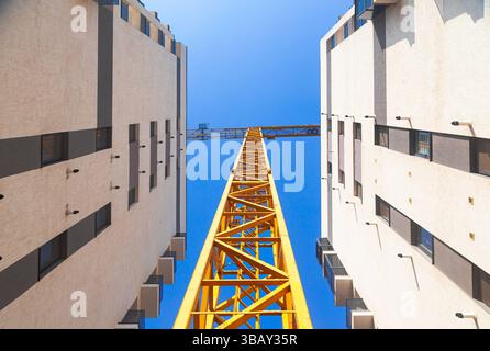 Two high-rise residential buildings under construction and a tower crane between them, view from below. Stock Photo