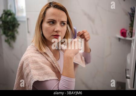 Woman combing her hair after shower in the bathroom Stock Photo