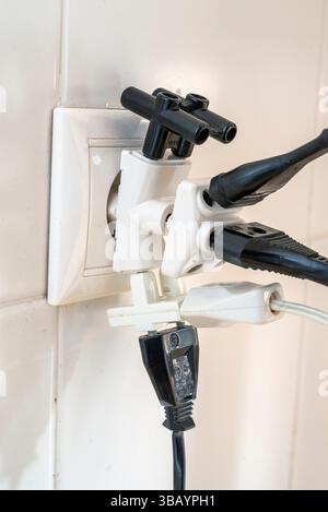 Overloaded electrical outlet with multiple plugs connected, illustrating energy use and potential safety hazards. Stock Photo