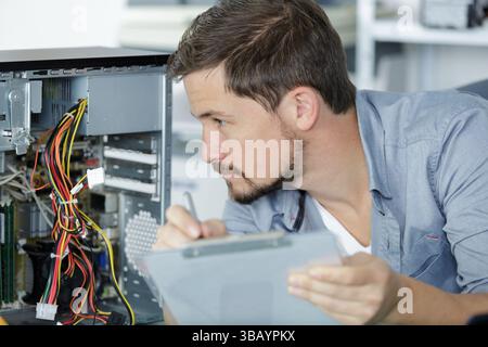 computer repairman installing new hard disk drive in laptop Stock Photo
