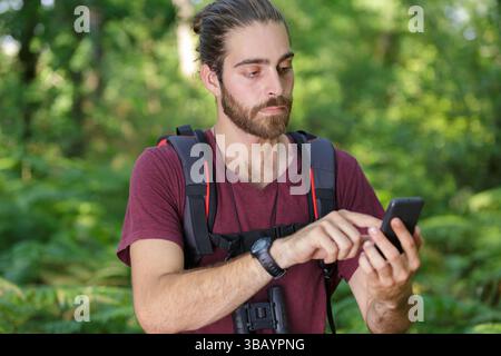 male hiker using mobile phone in forest Stock Photo
