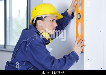 female builder using a spirit level Stock Photo