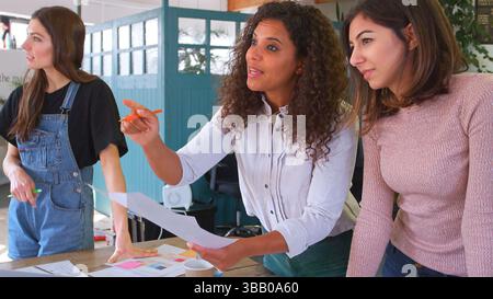 Multi-Cultural Female Business Team Meeting In Office Discussing Documents Stock Photo