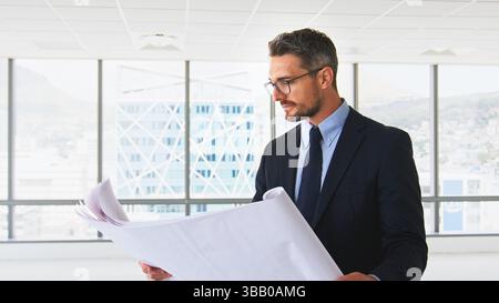 Male Architect Looking At Building Plans In Modern Office Stock Photo