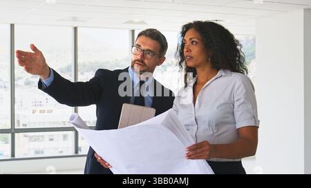 Male And Female Architects Meeting And Discussing Building Plans In Modern Office Stock Photo