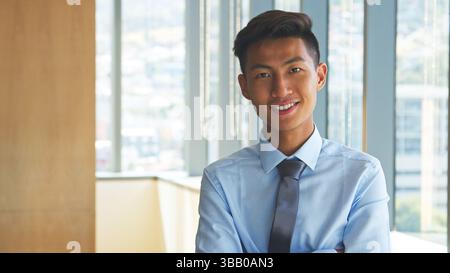 Portrait Of Smiling Businessman Wearing Shirt And Tie Standing In Modern Office Stock Photo