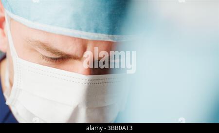 Close Up Of Male Surgeon In Hospital Wearing Mask And Gown Stock Photo