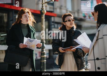 Multicultural business women discussing project strategies in an outdoor city setting Stock Photo