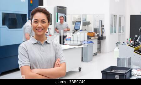 Portrait Of Female Engineer On Factory Floor Of Busy Workshop Stock Photo