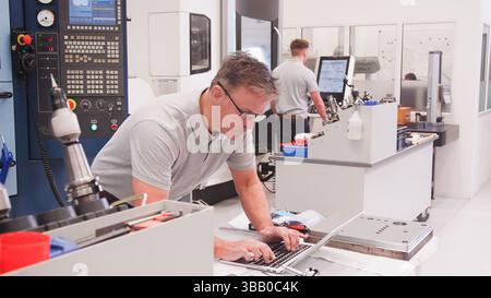 Mature Male Engineer In Factory Using CAD Programming Software On Laptop Stock Photo