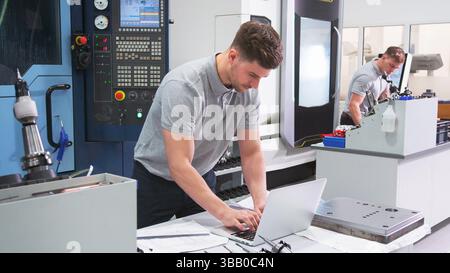 Male Engineer In Factory Using CAD Programming Software On Laptop Stock Photo