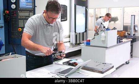 Mature Male Engineer In Factory Using CAD Programming Software On Laptop Measuring Component Stock Photo