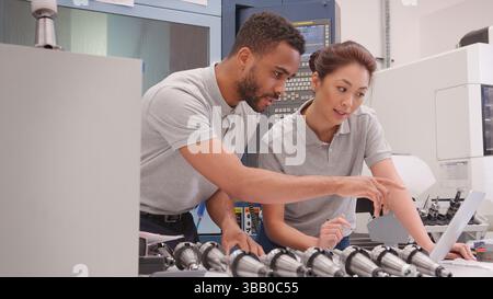 Male And Female Engineers Discussing Plans For Job Whilst Looking At Laptop Stock Photo